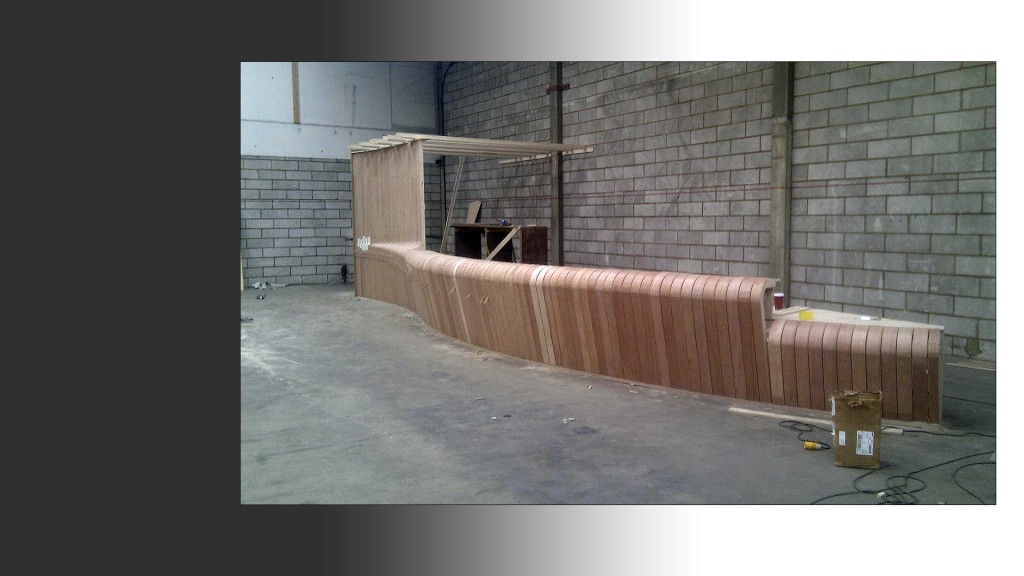 Large reception desk in the making with hundreds of birch ply ribs creating a curved surface
